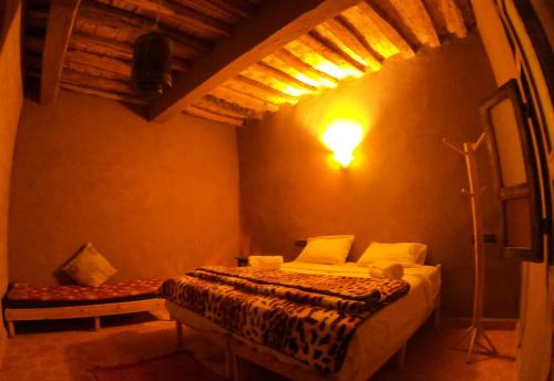 a bedroom with a bed in a room with a ceiling at Auberge Kasbah Dar Sahara Tours in Mhamid