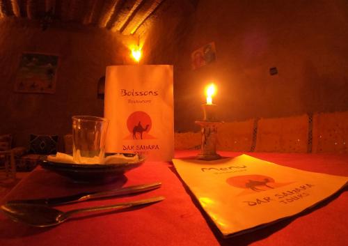 a table with a candle and a plate of food and a candle at Auberge Kasbah Dar Sahara Tours in Mhamid