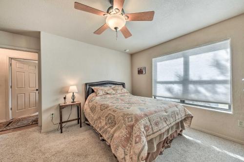 a bedroom with a bed with a ceiling fan and a window at Charming Ruidoso Home with Deck and Lovely Views! in Ruidoso