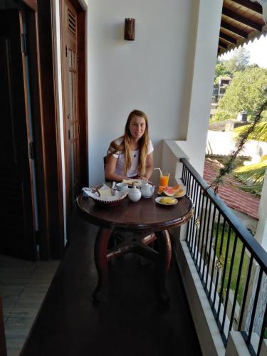 a woman sitting at a table on a balcony at Kandy City Village in Kandy