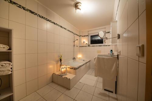 uma casa de banho em azulejos brancos com uma banheira e um lavatório. em Ferienwohnung-Auszeit-im-Schwarzwald em Schwanau