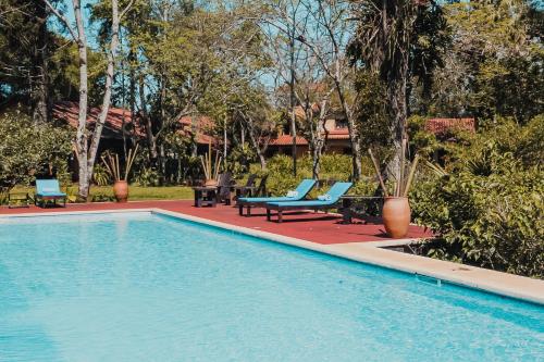 a swimming pool with blue lounge chairs next to a resort at Reserva Natural Iguazú - Posada Puerto Bemberg in Puerto Libertad