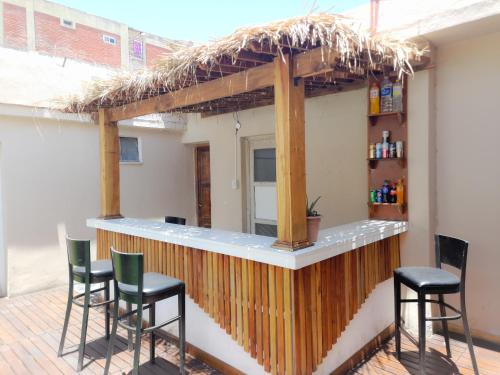 a bar with four stools and a thatched roof at Hotel TOTEM Boutique in Termas de Río Hondo