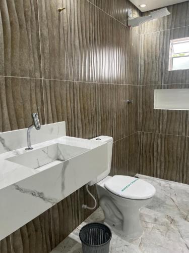 ein Badezimmer mit einem weißen WC und einem Waschbecken in der Unterkunft Hotel Ellos in Itaquaquecetuba