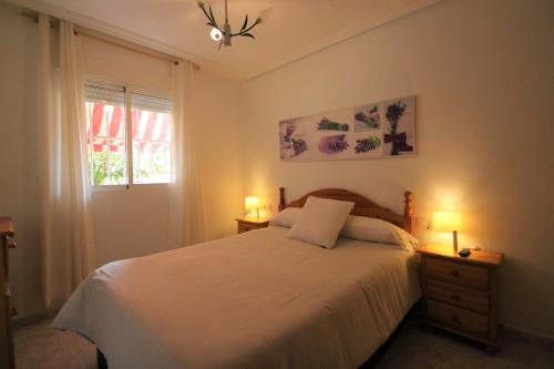 a bedroom with a bed with two lamps and a window at Apartamento CasaTuris en Playa Lisa Santa Pola SP101 in Santa Pola