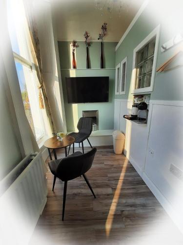 a living room with a table and chairs and a fireplace at Highlander House Boutique Hotel in Rothesay