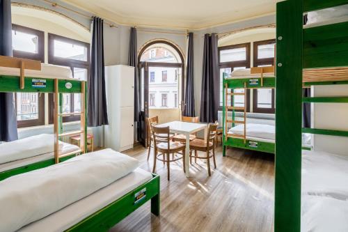 Schlafsaal mit Etagenbetten und einem Tisch in der Unterkunft Hostel Mondpalast in Dresden