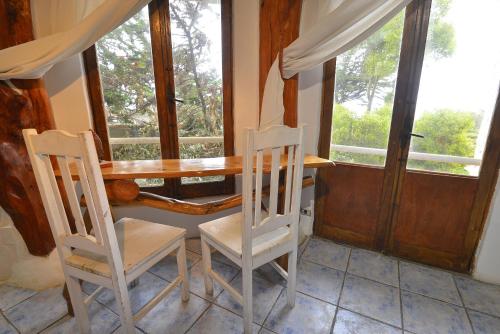 a dining room table with two chairs and two windows at Casa Cuento in Concón