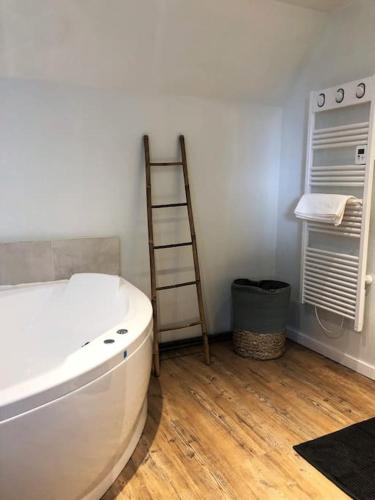 La salle de bains est pourvue d'une baignoire blanche et d'une échelle. dans l'établissement Appartement au calme entre Terre et Mer. Proche Honfleur (5min) Deauville (15min), à Barneville-la-Bertrand