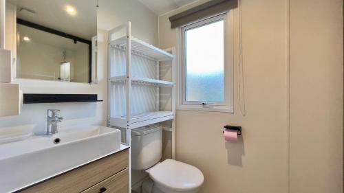 a bathroom with a toilet and a sink and a window at Mobil-Home Les Lauriers Roses Camping Siblu 4**** in Fréjus