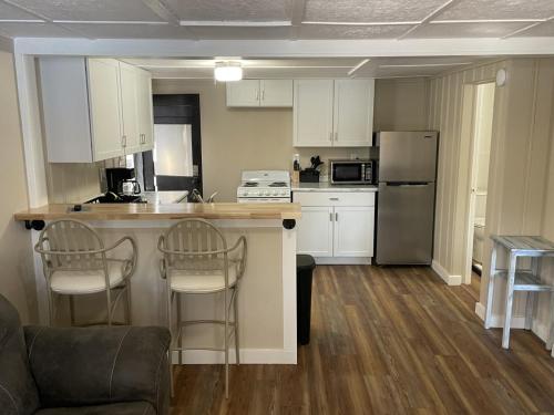 a kitchen with white cabinets and a counter with chairs at Lakeshore Fishing cabin 1 , dock/boat slip, fire pit. in Lake Ozark