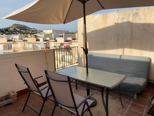 un tavolo e sedie con ombrellone su un balcone di Vistas al mar a El Campello