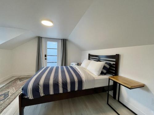 a bedroom with a bed with a table and a window at Salt Loft - Oceanfront, Hot Tub And Firepit! in Ucluelet