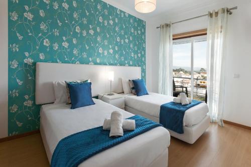 Paradise Place في نازاريه: غرفة نوم بسريرين باللونين الأزرق والأبيض