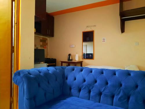 un sofá azul sentado en una sala de estar en Lola's Nest along the Highway - Free Parking, Wifi, Netflix & Rooftop views en Kikuyu