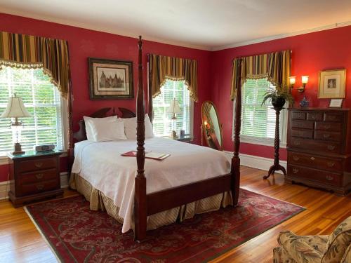 a bedroom with a bed with red walls and windows at Historic Rosemont Manor in Berryville