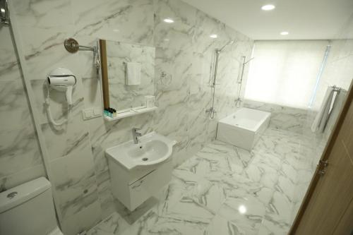 a white bathroom with a sink and a shower at El Emin İstanbul Hotel in Istanbul