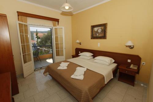 a bedroom with a bed with two towels on it at Perros Hotel in Agios Stefanos