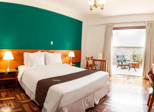 Un dormitorio con una cama grande y una pared verde en Dorado Hotel Boutique - Tacna en Tacna