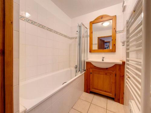 une salle de bain avec un lavabo, une baignoire et un miroir dans l'établissement Appartement spacieux Départ ski aux pieds Terrasse - FR-1-344-792, aux Menuires