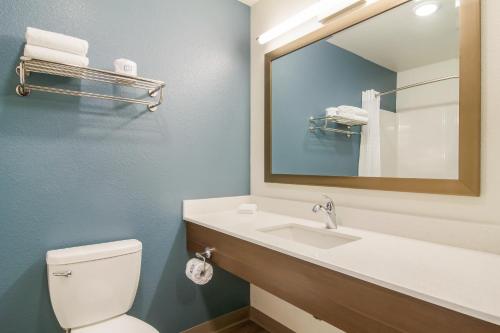 a bathroom with a toilet and a sink with a mirror at WoodSpring Suites Greensboro - High Point North in Greensboro