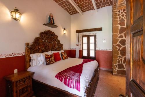 a bedroom with a large bed with a wooden headboard at Hacienda Maria Eugenio in Guanajuato