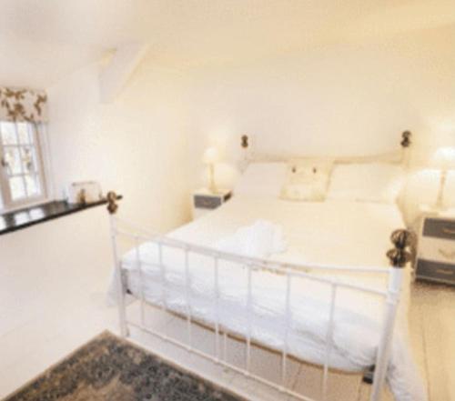 a white bed in a white bedroom with a window at Cosy Cottage Real Fire Nearby Pub Garden Parking in Altarnun