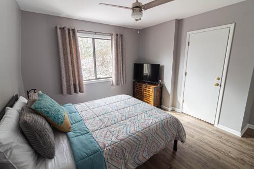 a bedroom with a bed and a television and a window at Pinetop Nest: Happy Place in Sugar Mountain in Banner Elk