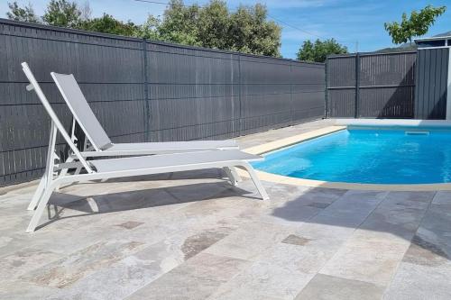 una silla blanca sentada junto a una piscina en CASA KHAMSA avec piscine privée, en Le Boulou