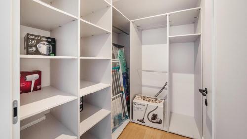 a white walk in closet with white shelves at Aqua Polanki Bodnar Apartments in Kołobrzeg