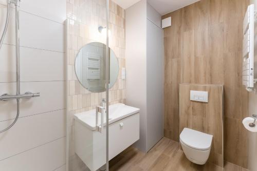 a bathroom with a toilet and a sink and a mirror at Aqua Polanki Bodnar Apartments in Kołobrzeg