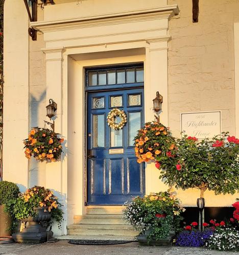 a blue front door of a house with flowers at Highlander House Boutique Hotel in Rothesay