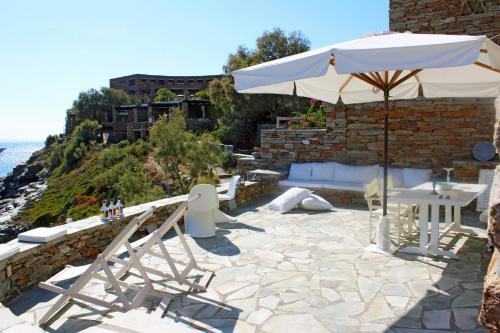 a patio with an umbrella and tables and chairs at Romantic and cozy house on the waterfront in Koundouros, Kea in Koundouros