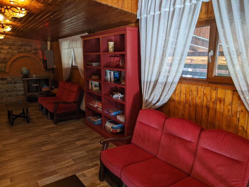 a living room with a red couch and a book shelf at Dorul Pescarului in Curtea de Argeş