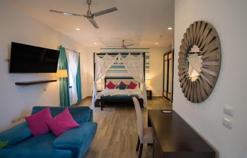 sala de estar con sofá azul y cama en Posada Mariposa Boutique Hotel - 5th Avenue en Playa del Carmen