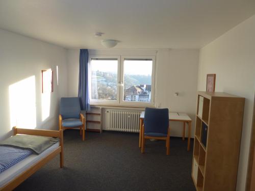 een slaapkamer met een bed en 2 stoelen en een raam bij Comfort Apartment in Tübingen