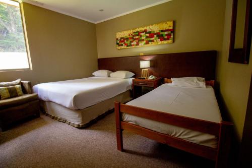 een hotelkamer met 2 bedden en een stoel bij Hotel Nevados de Chillan in Nevados de Chillan