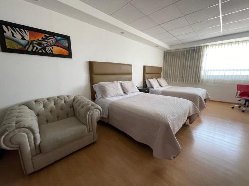 a hotel room with two beds and a couch at My Home Suites in Celaya