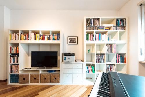 a living room with a television and book shelves at Sebino Guest House in Milan