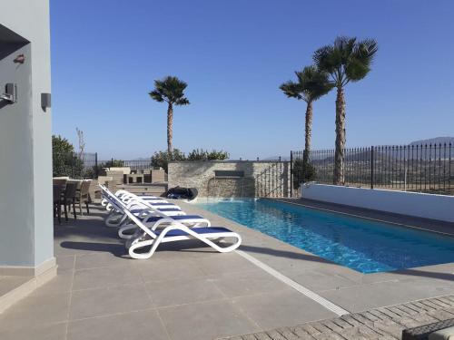 una fila di sedie a sdraio bianche accanto alla piscina di Finca La Mirage Coin a Coín