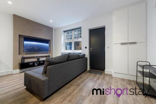 ein Wohnzimmer mit einem Sofa und einem TV in der Unterkunft The Residence Fitzrovia - Private One Bedroom Apartment With Own Entrance in London