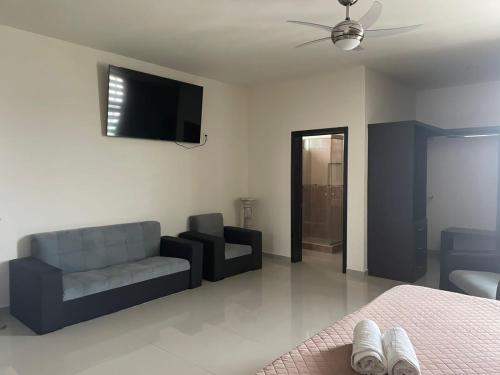 ein Wohnzimmer mit einem Sofa und einem TV an der Wand in der Unterkunft Suite Hotel San Salvador in San Juan de los Lagos