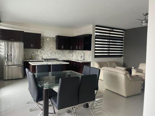 eine Küche und ein Wohnzimmer mit einem Glastisch und Stühlen in der Unterkunft Suite Hotel San Salvador in San Juan de los Lagos