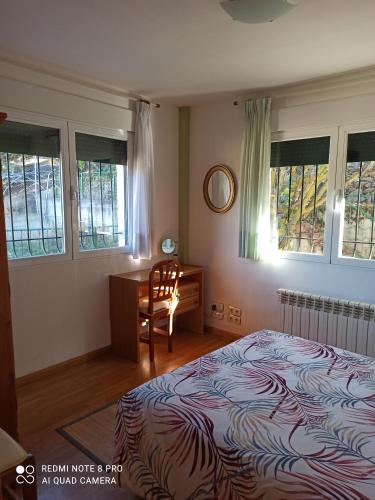 a bedroom with a bed and a desk and windows at Casa Las Bailas in Soria