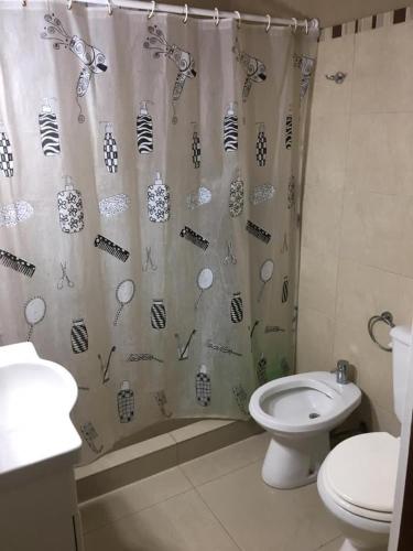 y baño con cortina de ducha y aseo. en Casa zona playa Necochea en Necochea