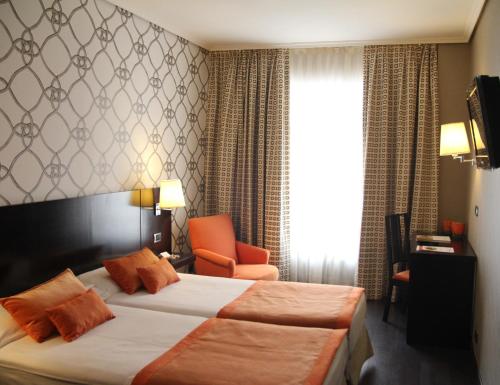 a hotel room with a bed and a chair at Hotel Conde Duque Bilbao in Bilbao