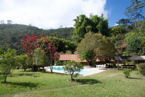 une piscine dans une cour avec des arbres et une maison dans l'établissement Casa em Friburgo com piscina lareira suíte & quarto, à Nova Friburgo