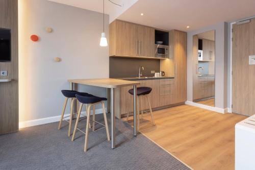 a kitchen with a table and stools in a room at Holiday Inn Express & Suites - Deventer by IHG in Deventer