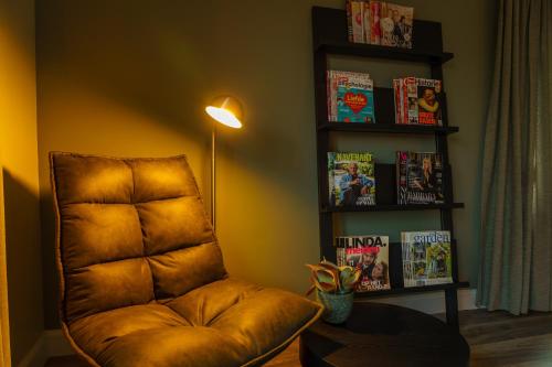 a living room with a brown chair and a book shelf at B&B De Boskamp in Tegelen