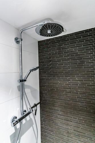 a shower in a bathroom with a brick wall at B&B De Boskamp in Tegelen